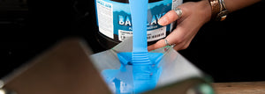 Person pouring a gallon of Baselayr Plastisol Emulsion into a scoop coater.